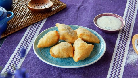 Ein Teller mit Samosas, drumherim Zutaten.
