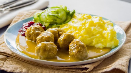 Eine Portion Körrbullar mit Dillgurken und Kartoffelpüree auf einem Teller.