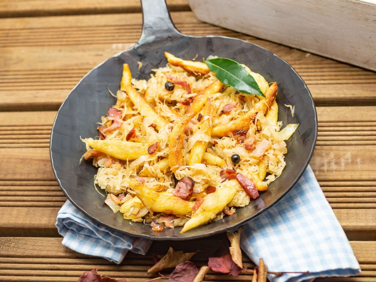 Flammkuchen-Schupfnudeln, serviert in einer Pfanne. Diese steht auf einer Serviette.