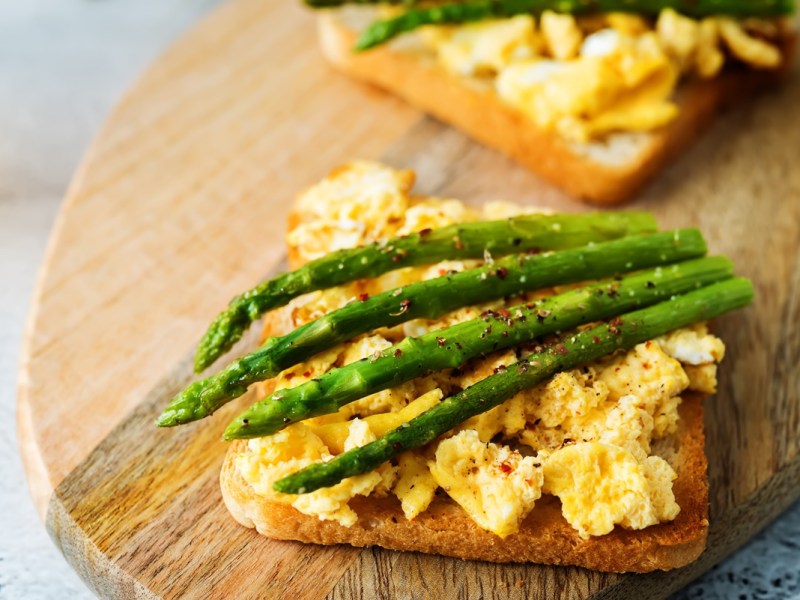 Spargel-Toast mit Rührei auf einem Holzbrett