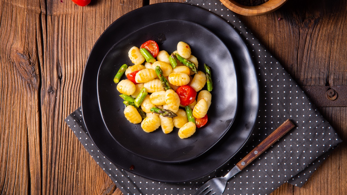 Spargel-Gnocchi-Pfanne auf schwarzem Teller.