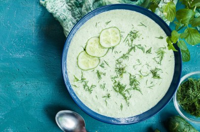 Schüssel mit kalter Spreewälder Gurkensuppe auf blauem Untergrund