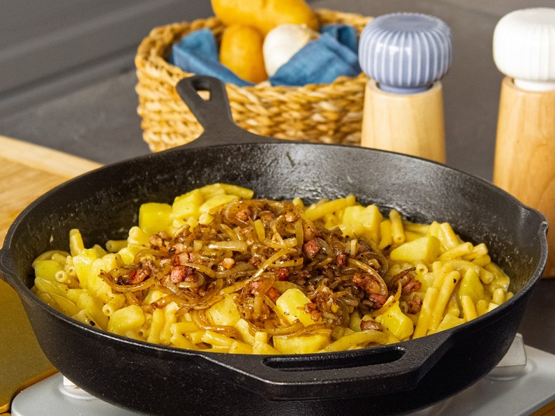 Älplermagronen mit Röstzwiebeln in einer gusseisernen Pfanne.