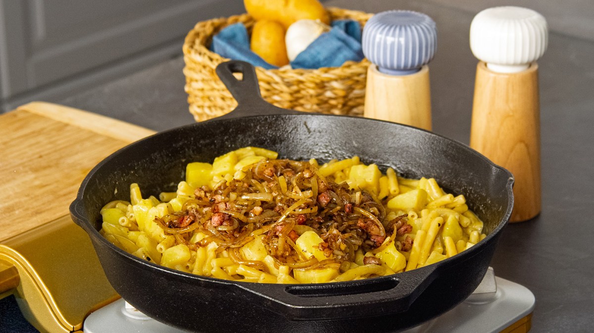 Älplermagronen mit Röstzwiebeln in einer gusseisernen Pfanne.
