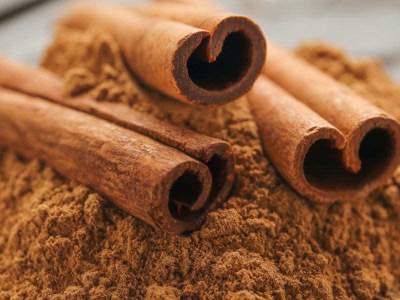 Jeden Tag Zimt essen: Einige Zimtrollen liegen auf einem Berg Zimtpulver.