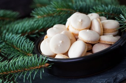 Eine Schüssel mit Anisplätzchen steht zwischen Tannenzweigen.