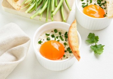 Eier im Glas, garniert mit Schnittlauch und einer Brotscheibe.