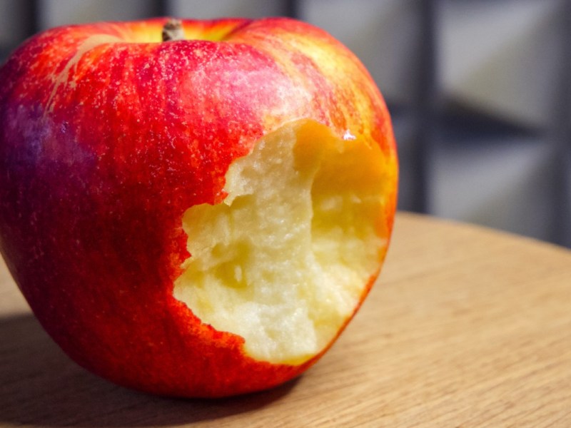Wie viele Äpfel am Tag: ein angebissener Apfel auf einer Tischplatte.