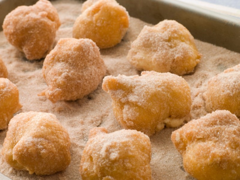 Mit Zimtzucker bestreute Ballbäuschen auf einem Blech.