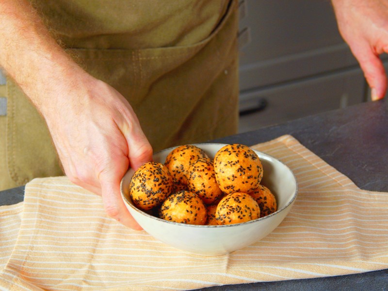 Ein Koch richtet frittierte Parmesanbälle in einer Schale an.