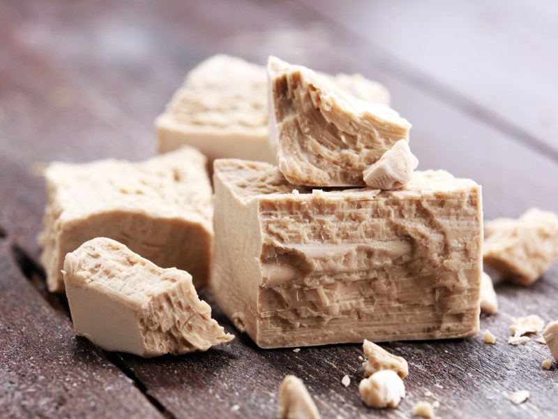 ist Hefe vegan: frische Hefe teilweise zerbröselt auf einem holzigen Untergrund.