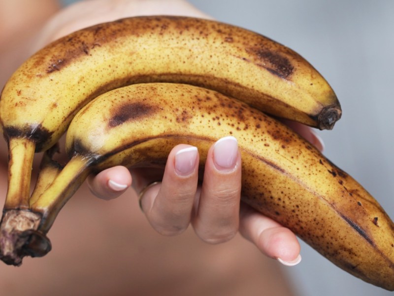 Reife Bananen verwerten: Frauenhand hält reife Bananen.