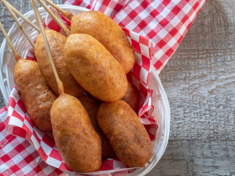 Mehrere vegane Corn Dogs in einem ovalen Korb. In der Draufsicht.