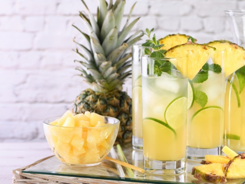 Zwei Gläser Wirbelwind, mit Ananasstücken und Minze garniert.