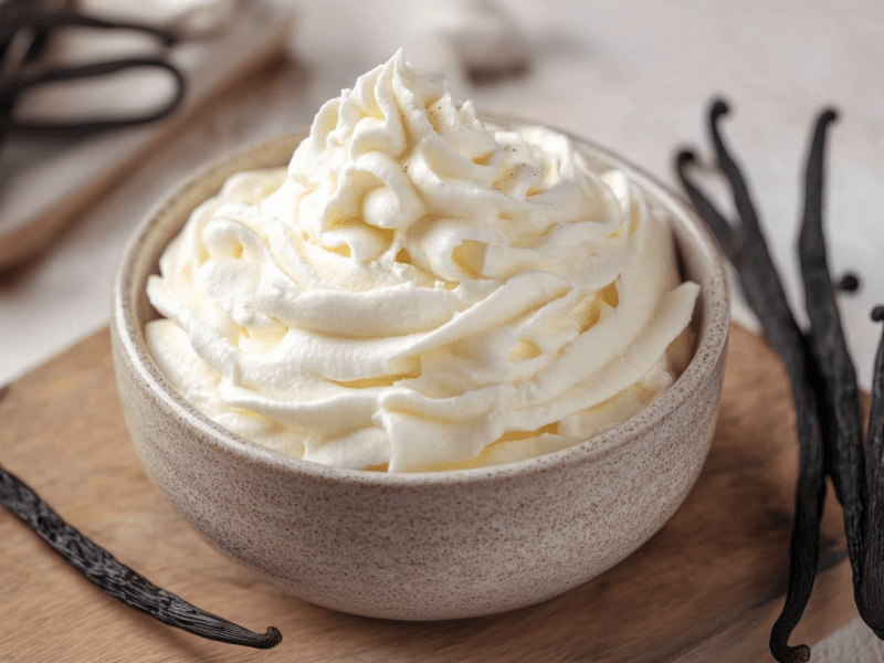 Crème Chantilly in einer hellen Schüssel. Drum herum liegen Vanilleschoten.