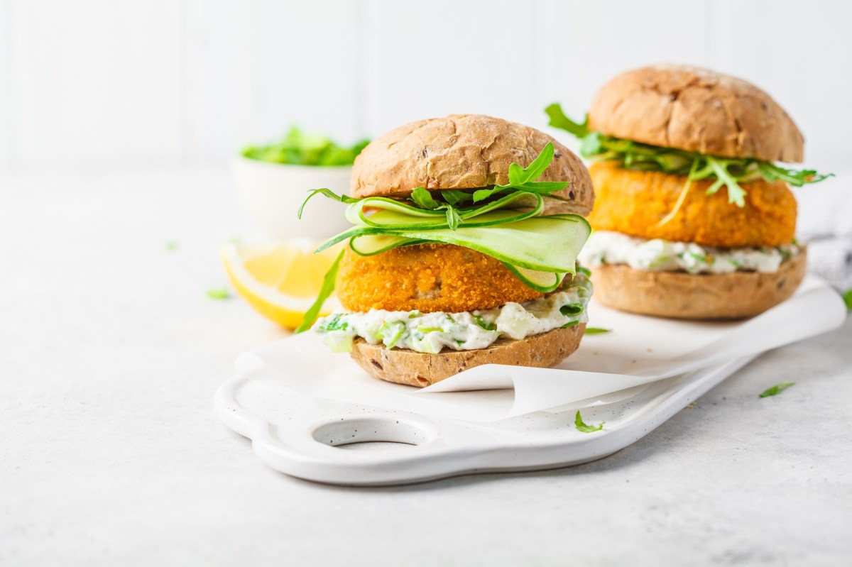 Zwei Fisch-Burger auf einem weißen Porzellantablett mit hellem Hintergrund.
