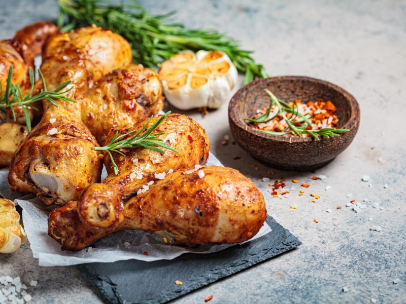 Harissa-Hähnchen vom Blech, serviert mit Zitronenspalten und Kirschtomaten.