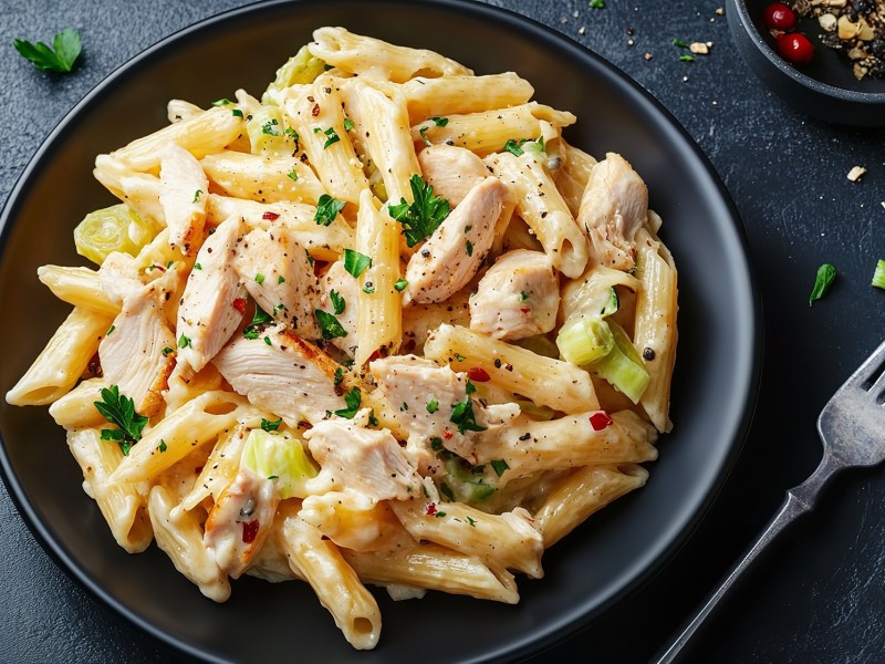 Teller mit Nudeln in Hähnchen-Lauch-Soße, Gabel daneben