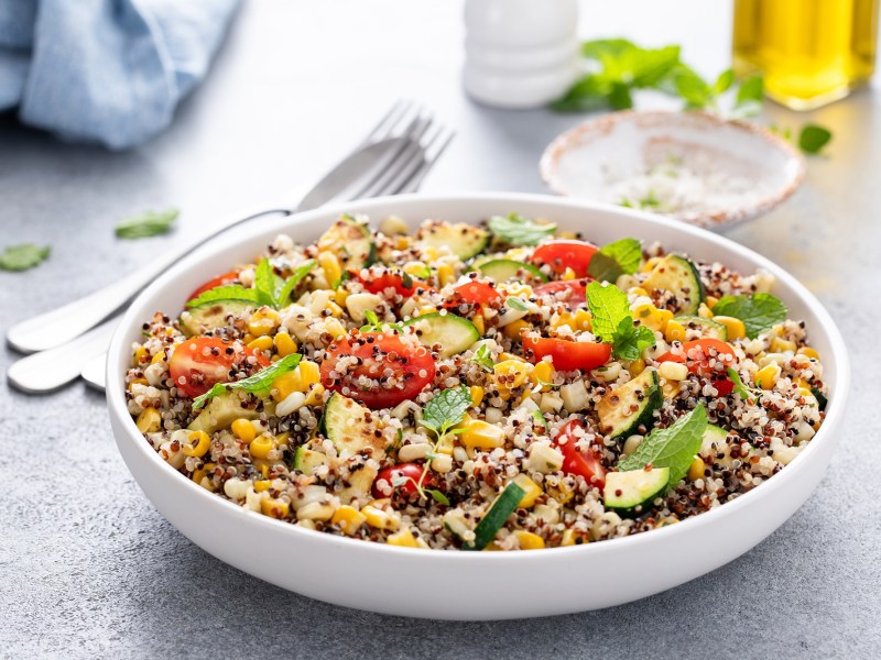 Eine Schüssel warmer Quinoasalat mit Tomaten und Mais.