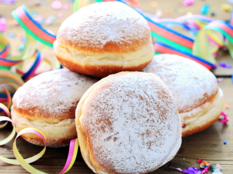 Rezept für Berliner: Mehrere Berliner mit Orangencreme sind übereinander gestapelt. Drumherum liegt Partydeko.