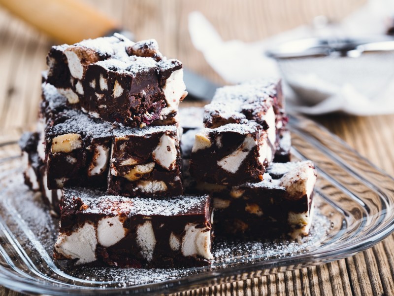 Einige Stücke Rocky-Road-Schokoriegel mit Marshmallows auf einem Glasteller.