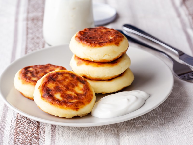 Syrniki: ukrainische Quarkpfannkuchen auf einem Teller.