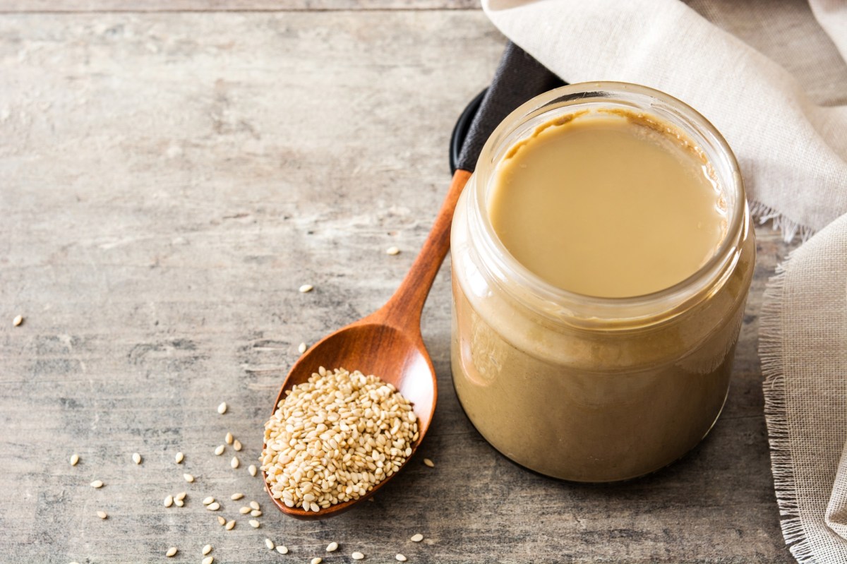 Tahini selbst machen: ein Glas Tahini mit Sesamsaat daneben.