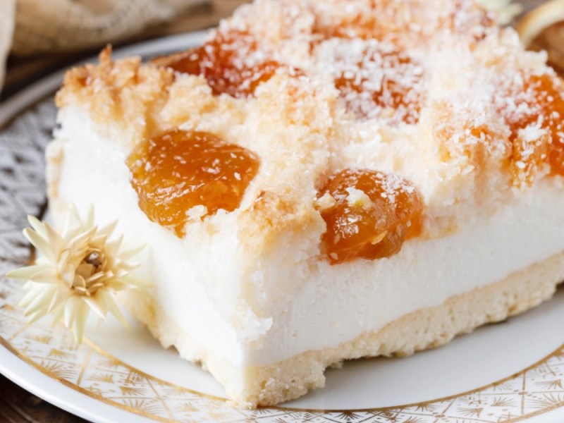 Ein Stück Aprikosen-Quarkschnitte mit Kokos auf einem Teller.