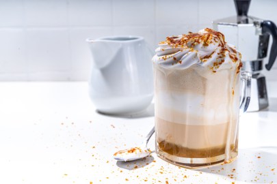 Glas mit Crème-brûlée-Latte, Espressokocher im Hintergrund