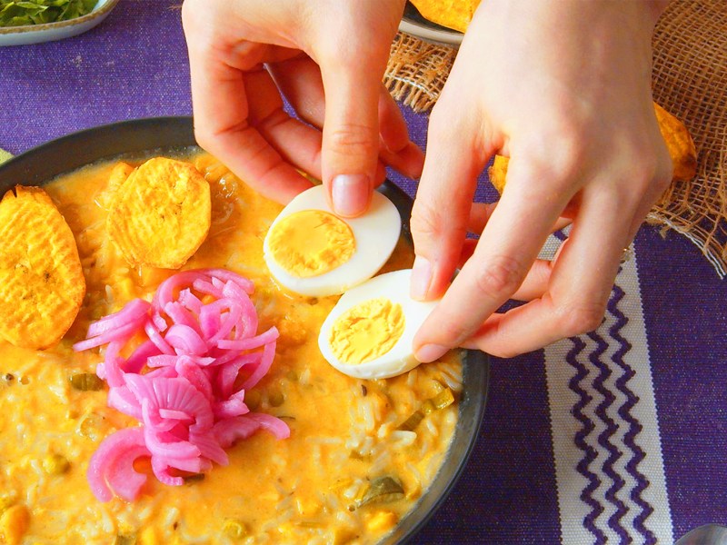 Eine Köchin legt halbierte Eier auf eine Schüssel mit Fanesca.
