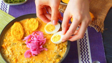 Eine Köchin legt halbierte Eier auf eine Schüssel mit Fanesca.