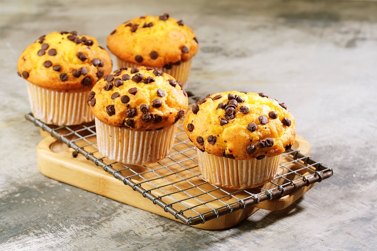 4 Haferflocken-Schoko-Muffins auf einem Kuchengitter, das auf einem Holzbrett steht.