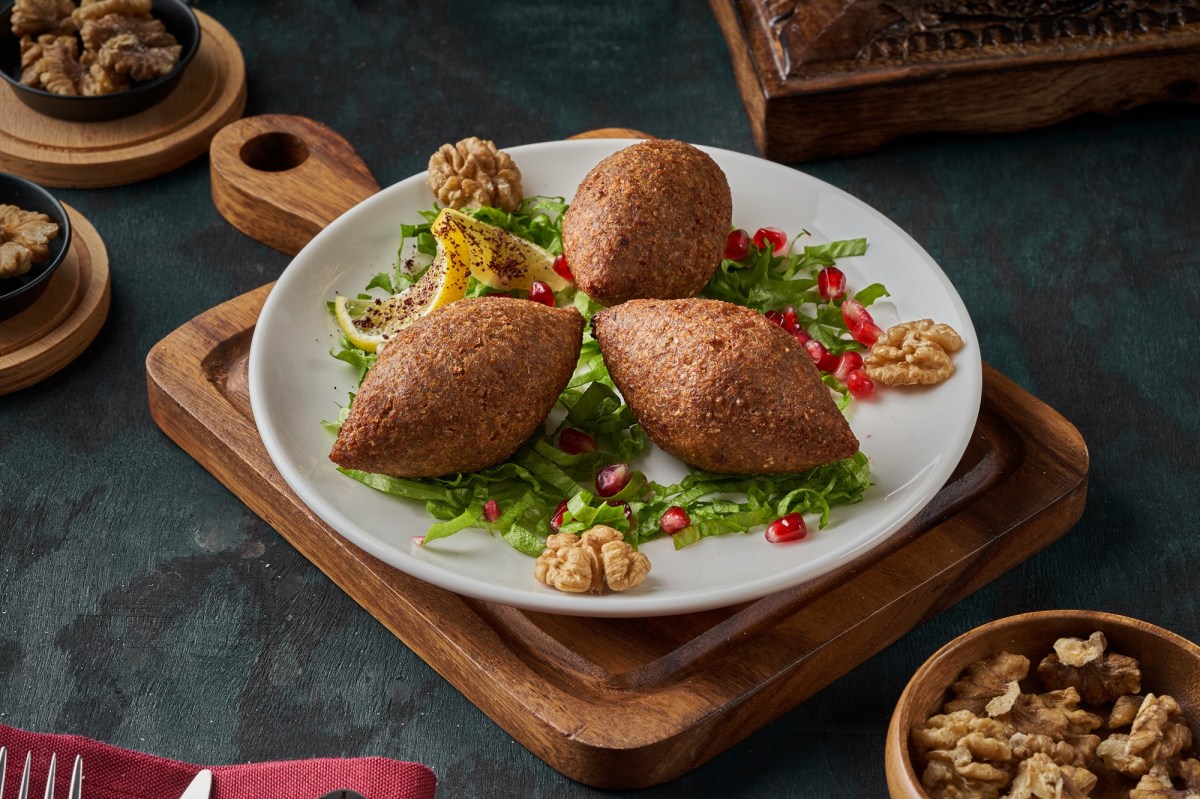 Drei levantinische Kibbeh: Bulgur-Hackfleisch-Bällchen auf einem Teller, serviert mit Zitrone.