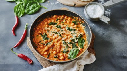 Ein Kichererbseneintopf mit Harissa in der Draufsicht. Drumherum frische Zutaten.