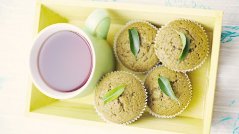 Mehrere Matcha-Muffins neben einer Tasse Tee in der Draufsicht.