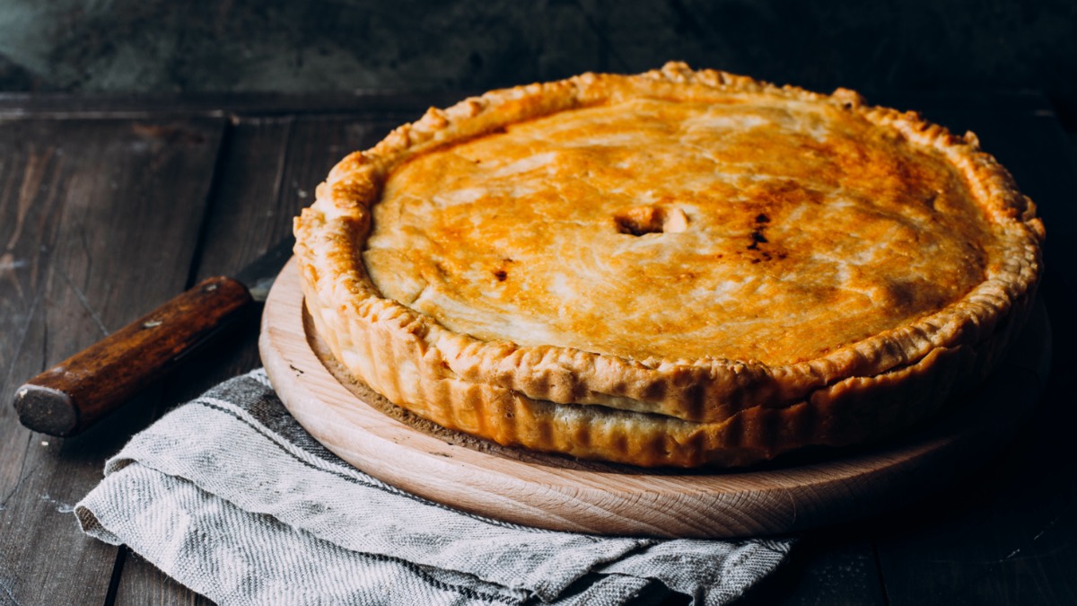 Ein Rindfleisch-Pie auf einem runden Holzbrett.