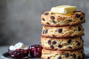 Stapel Rosinen-Scones mit Erdbeermarmelade und Clotted Cream daneben