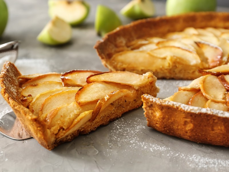 Schmand-Apfelkuchen ohne Mehl, von dem schon ein Stück entnommen wurde.