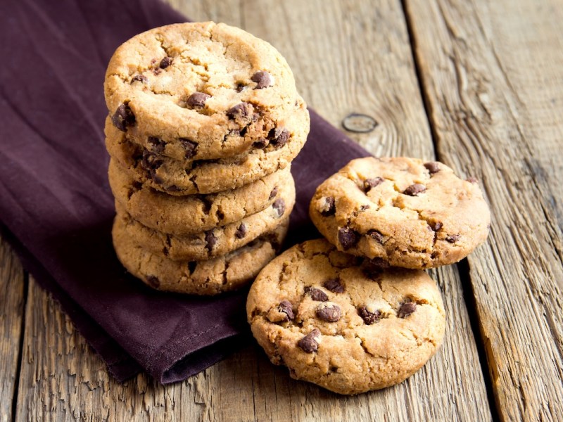 Ein Stapel Schokobon-Kekse mit weißer und dunkler Schokolade auf einer violetten Serviette aus Stoff.