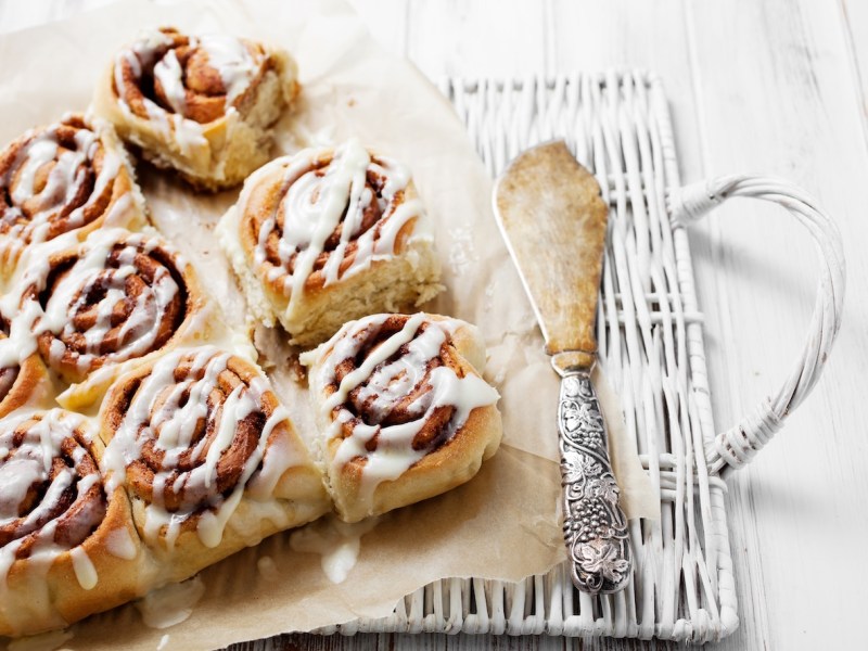 Mehrere Zimtschnecken mit Eierlikör auf Backpapier, daneben ein Tortenheber.