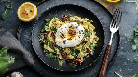 Bärlauch-Zitronen-Pasta mit Burrata auf einem Teller in der Draufsicht. Daneben liegen eine Gabel und eine halbe Zitrone.