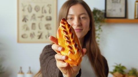 Eine Köchin hält ein gefülltes Brioche-Brötchen in die Kamera.