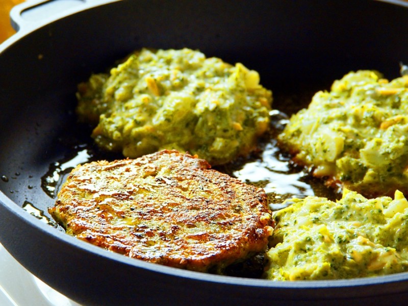 Vier Brokkoli-Bratlinge in einer Pfanne.