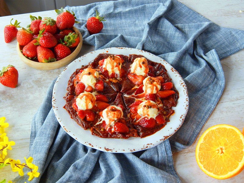 Ein Teller mit Erdbeer-Crêpes mit grünem Pfeffer, darauf mehrere Kugeln Vanilleeis.