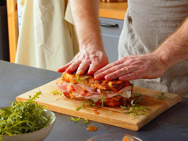 Ein Koch präsentiert ein aufgeschnittenes gefülltes Pizzabrot.