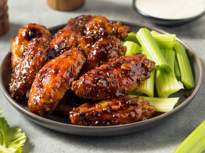 Honig-Knoblauch-Hähnchen mit Selleriestangen auf einem Teller.