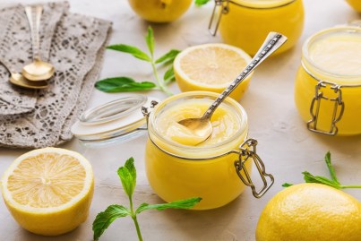 Lemon Curd selbst machen: Ein Glas Lemon Curd zwischen allerlei Zutaten.