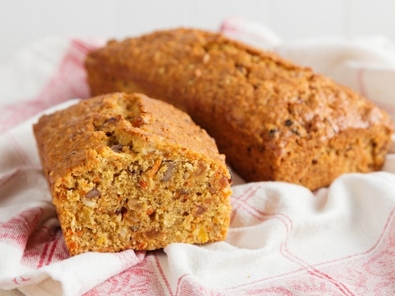Zwei Laibe Möhren-Apfel-Kuchen ohne Zucker auf einem rot-weißen Geschirrtuch.