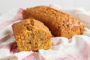 Zwei Laibe Möhren-Apfel-Kuchen ohne Zucker auf einem rot-weißen Geschirrtuch.