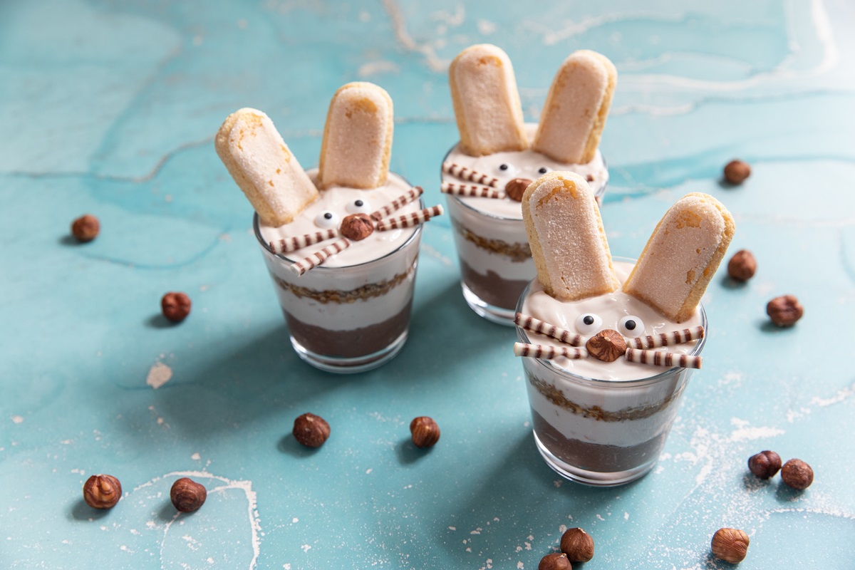 Einige Gläser Osterhasen-Tiramisu auf einem blauen Tisch.